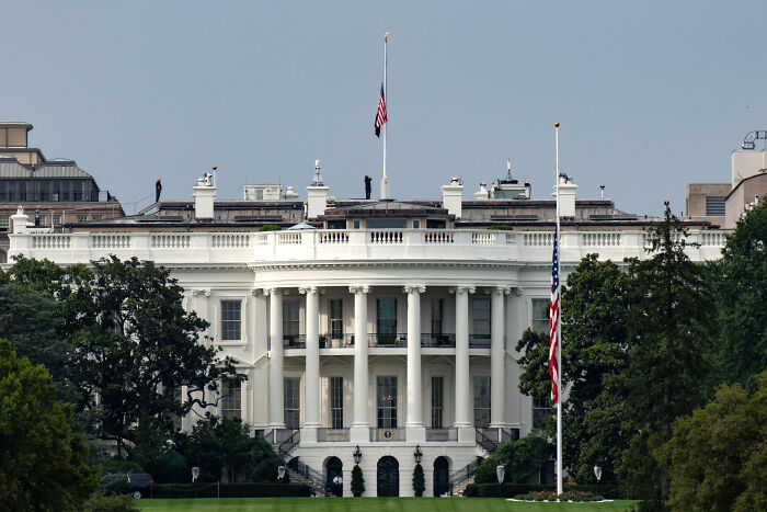 The White House with American flags at half-staff symbolizing concerns over America&rsquo;s escalating political violence.