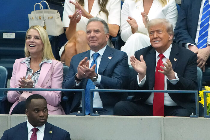 Donald Trump clapping at U.S. Open final with boos and cheers from the crowd during match delay.