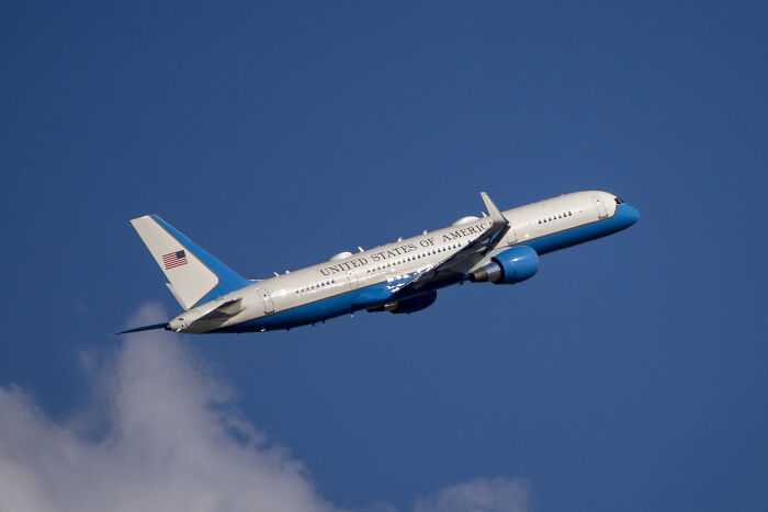Air Force Two in flight, representing VP JD Vance transporting Charlie Kirk's casket with US flag on the tail.