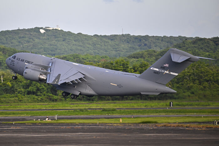 US Air Force cargo plane taking off with green hills in the background related to JD Vance&rsquo;s Venezuelan boat joke news.