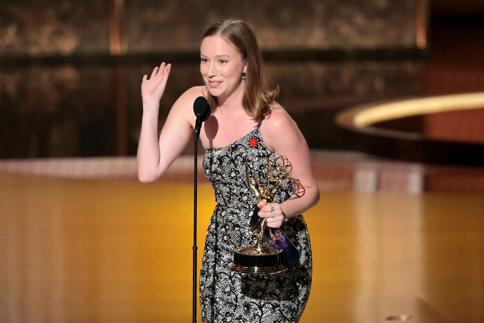Actress in a patterned dress holding an Emmy Award, speaking at a microphone during an awards ceremony praising Palestine speech.