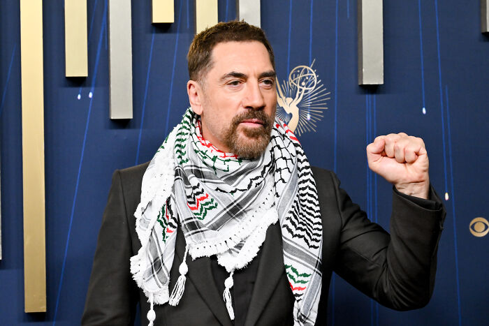 Javier Bardem on Emmys red carpet wearing a patterned scarf and raising fist advocating for Gaza ceasefire.