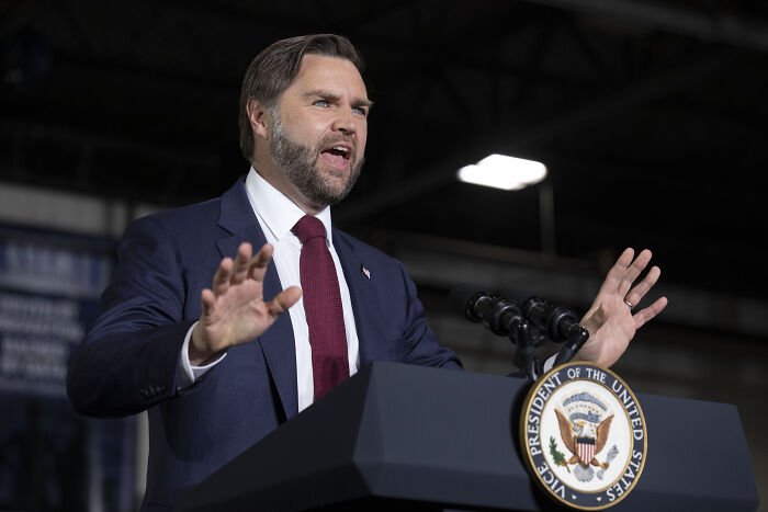 JD Vance speaking at a podium with Vice President seal, addressing controversy over Venezuelan boat joke and fishing remarks