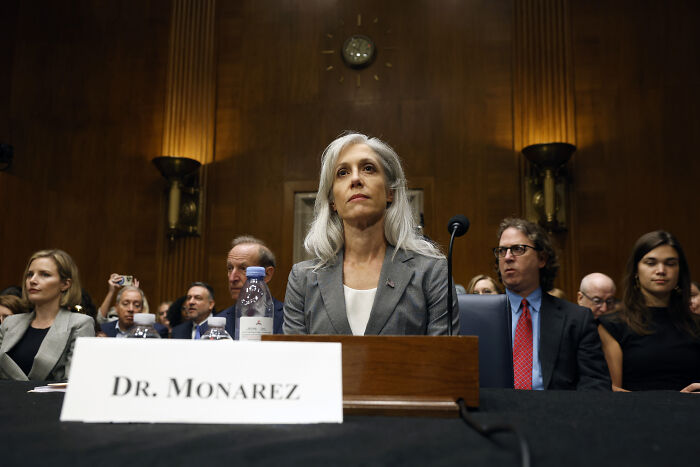 Dr. Susan Monarez at a hearing, facing forward and seated behind a nameplate, discussing CDC leadership and vaccine plans.