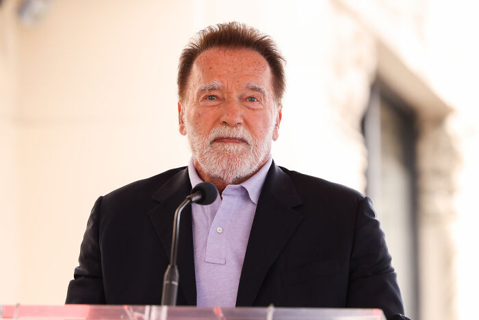 Arnold Schwarzenegger delivering a passionate speech at a podium, discussing Charlie Kirk and related concerns.