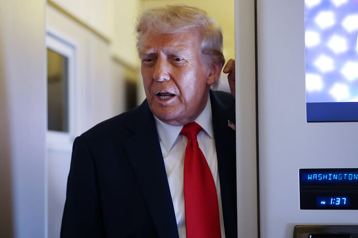 Donald Trump speaking in a suit and red tie, discussing TV networks and license revocation concerns.