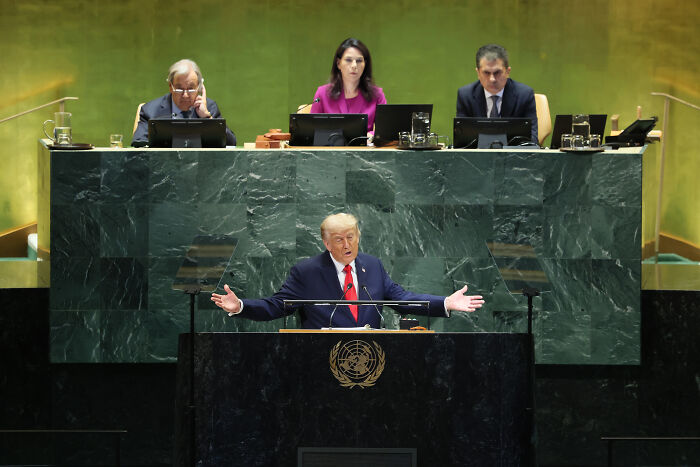 Donald Trump speaking at the UN General Assembly, addressing Europe on immigration with arms extended at the podium.