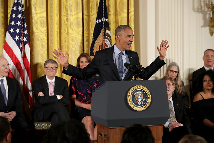 Barack Obama speaking at a podium with the presidential seal, discussing leadership among American presidents who waged war.