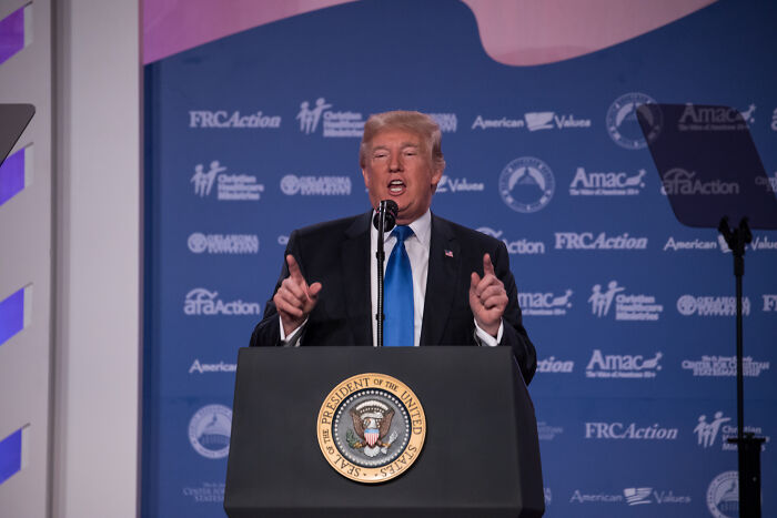 Donald Trump speaking at a podium with presidential seal, discussing US relations, Venezuela conflict concerns.