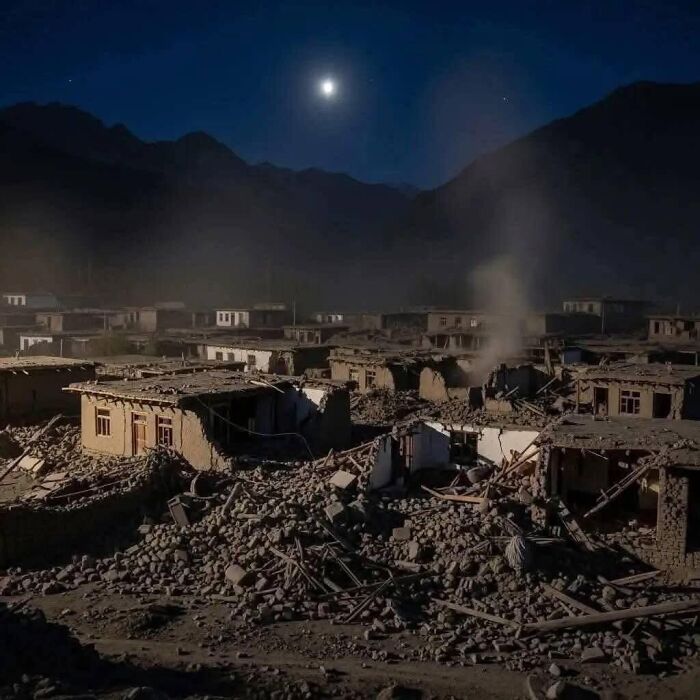 Collapsed buildings and debris at night under a bright moon as rescue teams race to save survivors after Afghanistan earthquake.