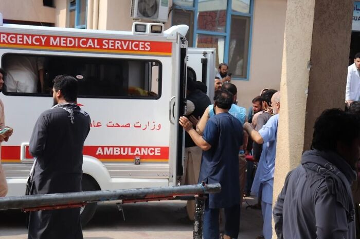 Emergency medical team next to ambulance assisting injured survivors after Afghanistan earthquake disaster response.