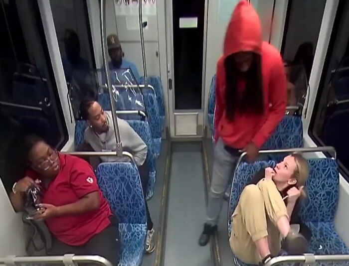 Ukrainian refugee on train showing fear and horror after being stabbed, with other passengers seated nearby.