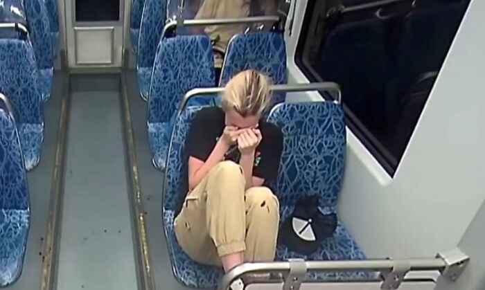 Ukrainian refugee showing final look of horror on train after being stabbed, sitting alone on blue patterned seats.