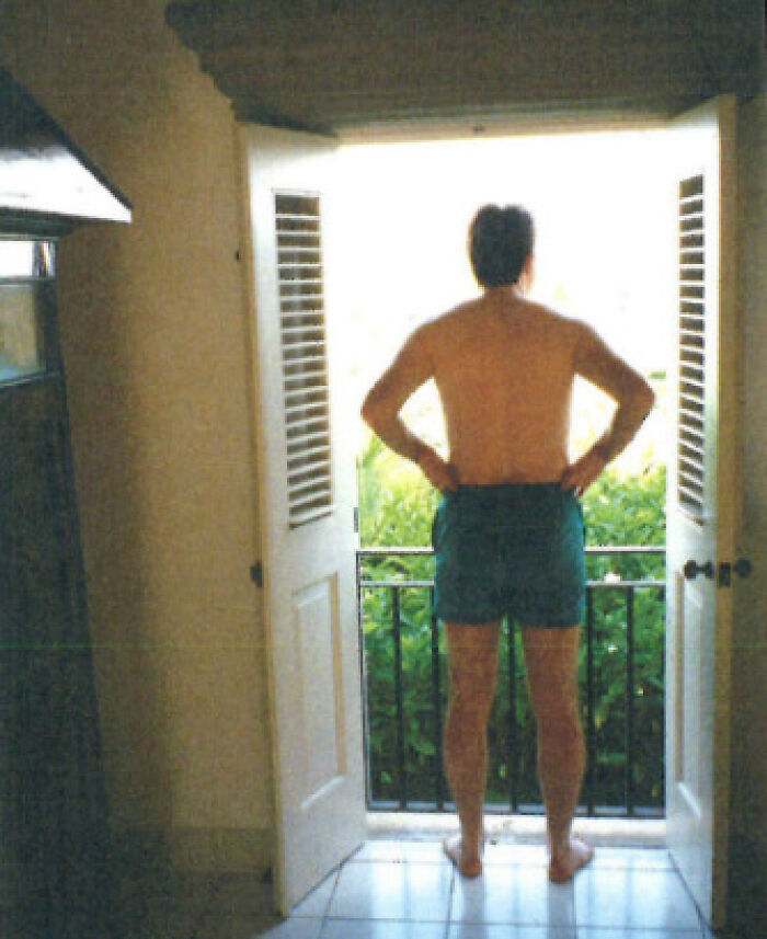 Man standing shirtless in shorts at an open balcony door, related to U.S. ambassador Jeffrey Epstein message controversy.