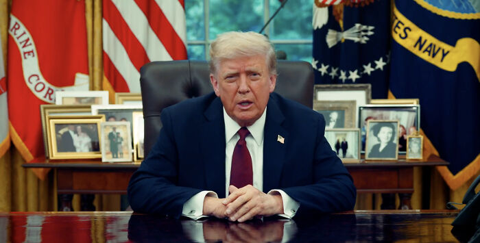 Donald Trump seated in the Oval Office, discussing Charlie Kirk, with glitches fueling accusations of using AI technology.