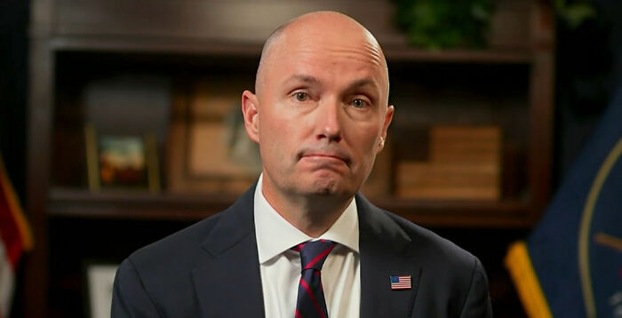 Governor speaking in formal setting, addressing Tyler Robinson refusing to cooperate in Charlie Kirk shooting investigation.