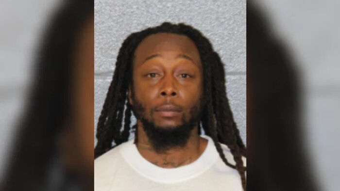 Mugshot of suspected Ukrainian refugee attacker with long dreadlocks and white shirt, speaking from jail.