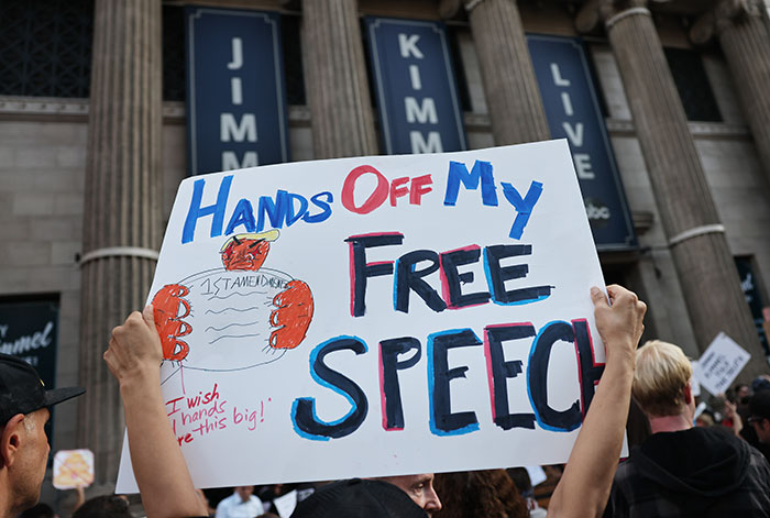 Protester holding a sign advocating for free speech during a public event about free-speech social media laws UK.
