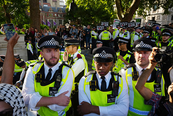 Police officers in bright vests managing a protest with signs, highlighting free speech social media laws UK issues.