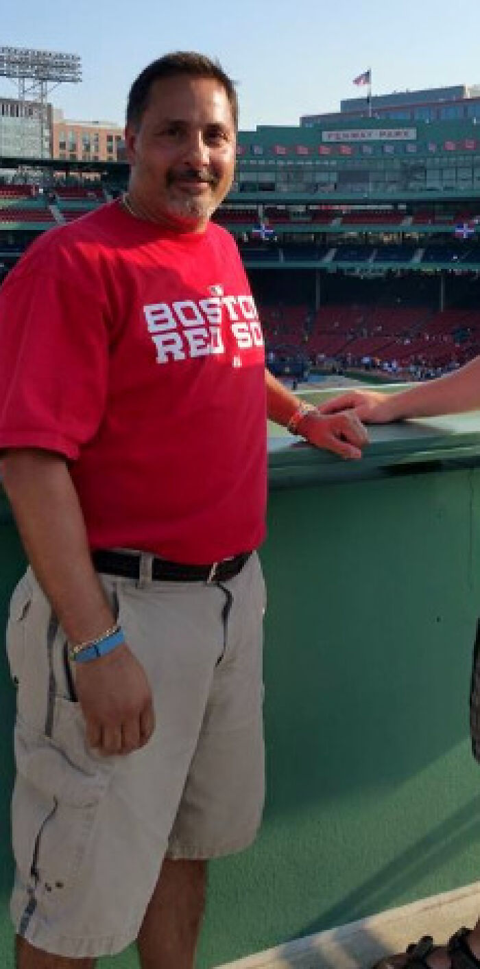Man wearing a red Boston Red Sox shirt standing at a sports stadium, related to New Hampshire country club shooting victim.