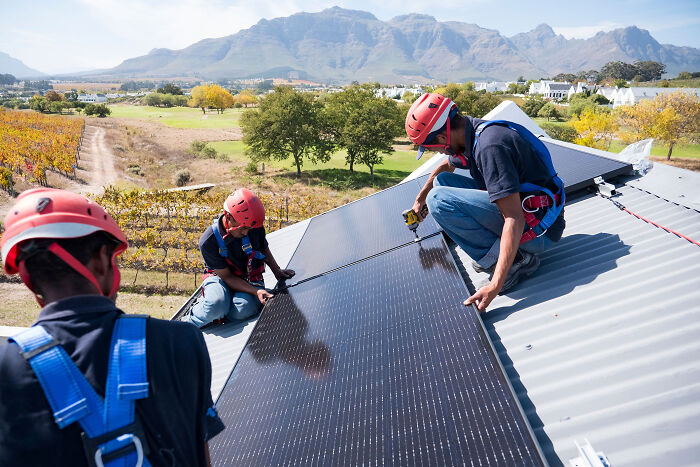 Workers installing solar panels on a rooftop as part of the solar power plant boom in Africa's renewable energy sector.