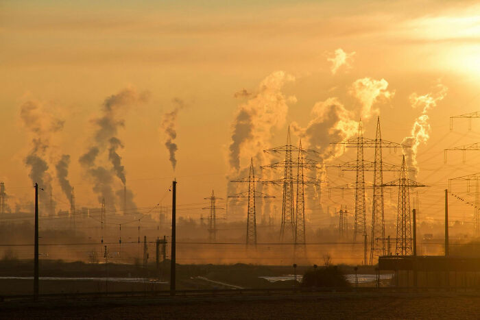 Industrial emissions with power lines during sunset, highlighting the need for solar power plant boom in Africa.