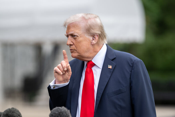 Donald Trump gesturing seriously outdoors, highlighting his hairstyle in a moment related to Time Magazine photo reaction.