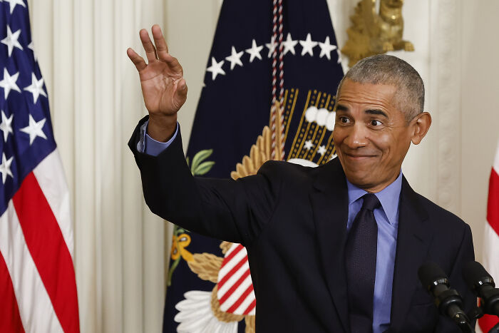 Barack Obama in a suit gesturing with his hand during a speech, related to Pelosi endorsement and Kamala Harris news.