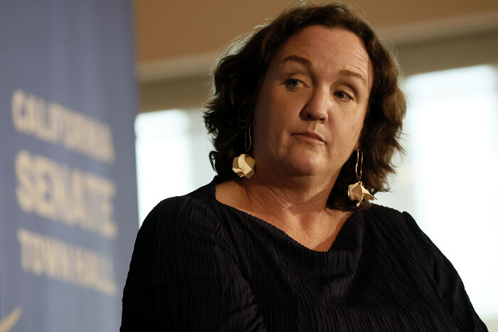 California governor hopeful Katie Porter at a townhall event, looking serious and engaged in discussion.