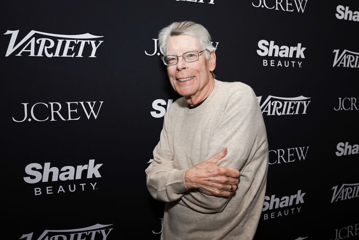 Stephen King wearing glasses and a beige sweater at a media event, linked to World Series Truth Social post controversy.