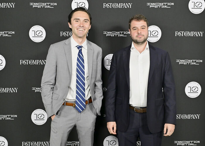 Two men in suits standing at a Fast Company Innovation Festival event, related to David Hogg PAC spending on consultants and fitness.