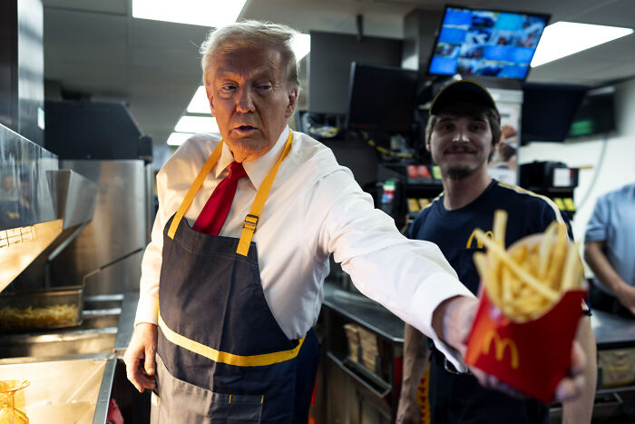 Donald Trump wearing apron serving McDonald's fries, linked to Newsom trolling Trump over fat troops remarks.