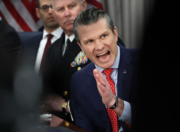 Man in blue suit and red tie speaking passionately during discussion as reporters stage mass walkout over Pentagon gag rules.