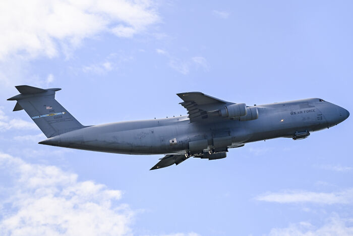 US Air Force cargo plane flying in clear sky amid skyrocketing tensions between US and Venezuela.