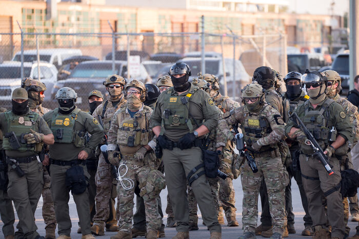 Federal agents in tactical gear assemble outside an apartment building during a Chicago immigration raid.