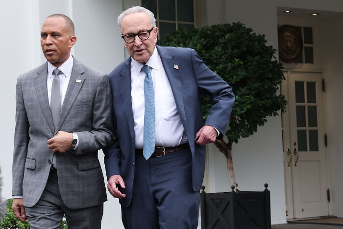 Two politicians walking outside a government building amid government shutdown talks and rising blame between Dems and GOP.