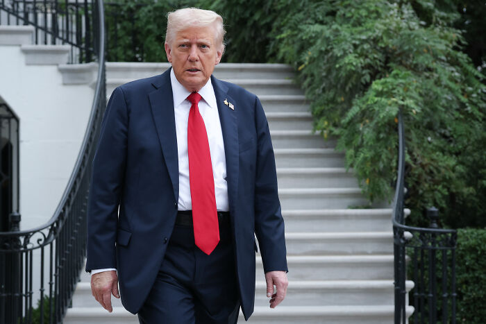 Former President Donald Trump walking outside near stairs, symbolizing government shutdown and political blame game.