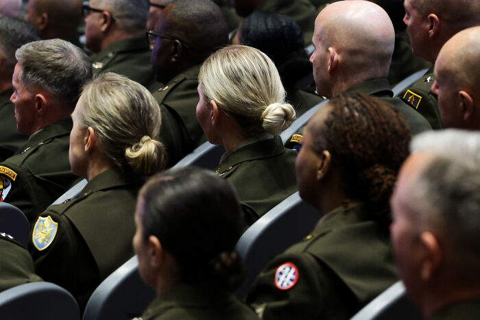 Military generals and personnel seated in uniform during a speech on U.S. cities as training grounds.