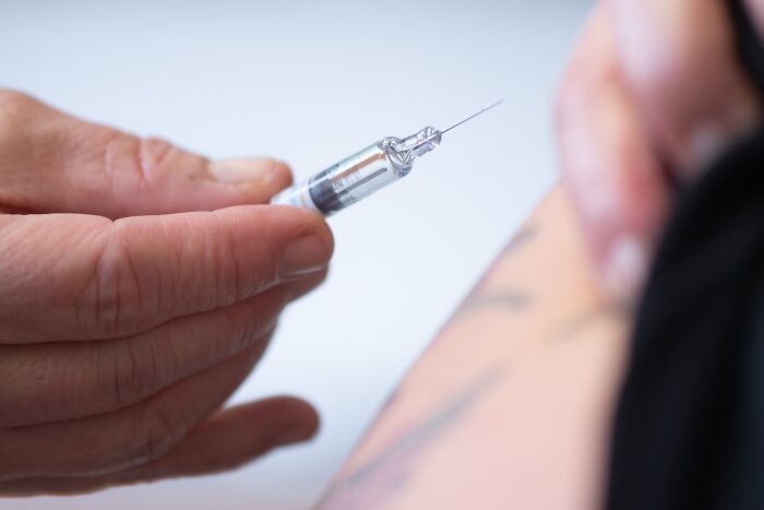 Hand holding syringe administering vaccine injection, related to infectious disease and whistleblower filing news.