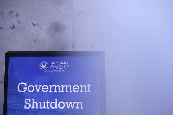 Signboard displaying Government Shutdown message outside a building with fog, highlighting government shutdown impact and political blame.