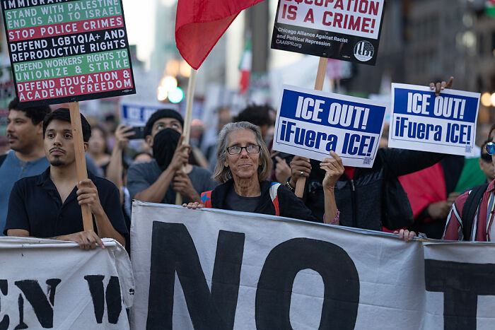 Protesters holding signs during a Chicago immigration raid as federal agents arrest 37 in an overnight operation