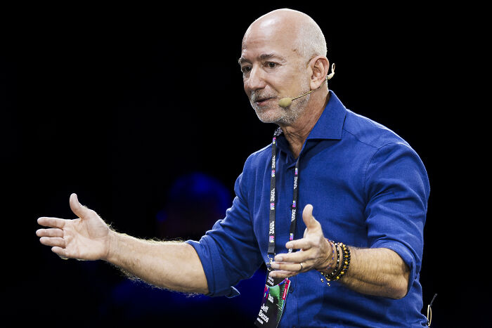 Man in blue shirt speaking with headset microphone at a conference, relating to Neil Young music protest against Amazon.