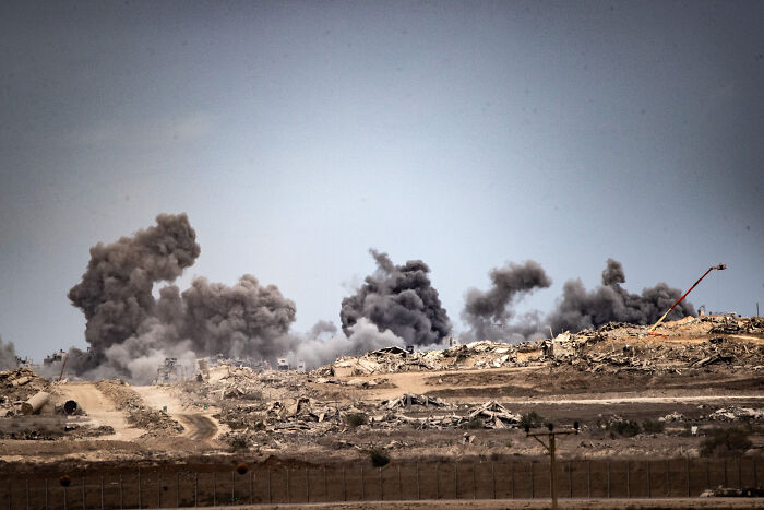 Smoke rising from explosions in a barren landscape amid doubts over Israel&rsquo;s ceasefire and Hamas hostage situation.