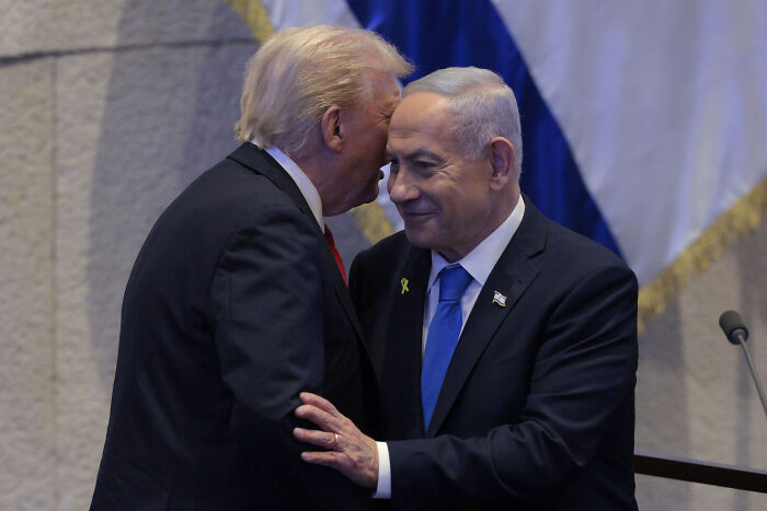 Donald Trump and Benjamin Netanyahu warmly greeting each other during a Knesset event with close interaction.