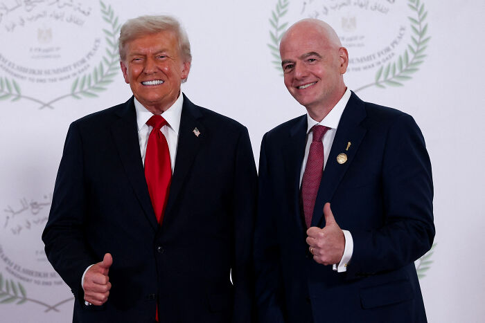 Donald Trump and a man in suits smiling and giving thumbs up at a formal event related to World Cup games in Boston.