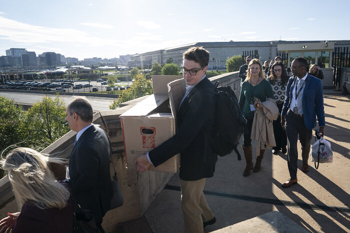 Reporters walk out of Pentagon carrying boxes and bags during mass protest against new Pentagon gag rules.