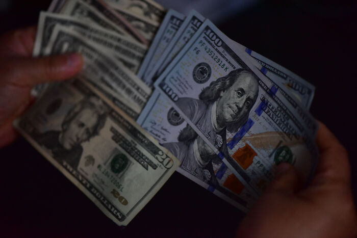 Hands holding US dollar bills representing FBI NBA gambling cases involving mafia money and insider bets.