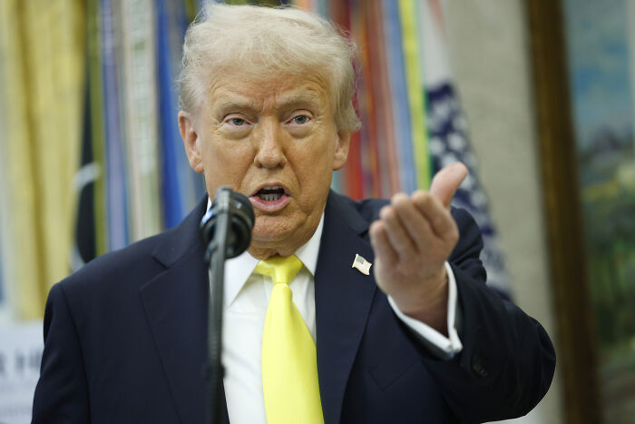 Former President Trump speaking at a podium, related to Danger Zone singer wanting song removed from King Trump video.