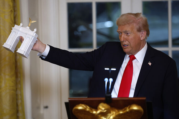 Donald Trump holding a model structure while speaking indoors, related to agency overseeing D.C. renovations.