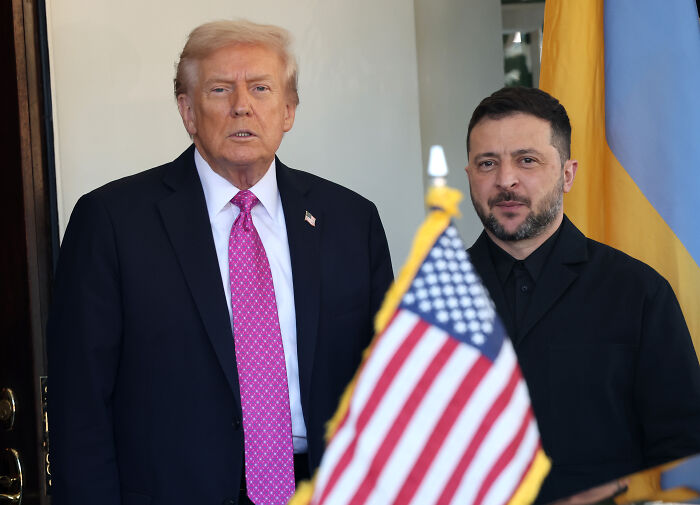 Donald Trump and Volodymyr Zelenskyy standing next to a US flag, highlighting Trump and Putin Budapest meeting context.